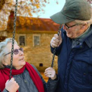 Elderly Couple Sat on Swings Outside