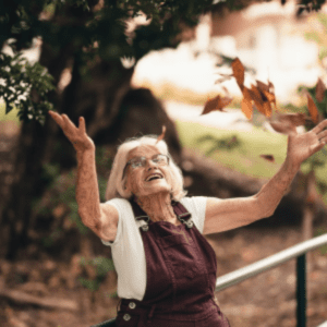 Elderly Woman Outdoors in Autumn Leaves